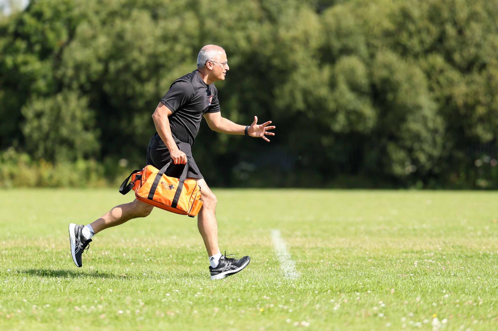 Dr Neeraj Sharma running onto the pitch with a medical bag